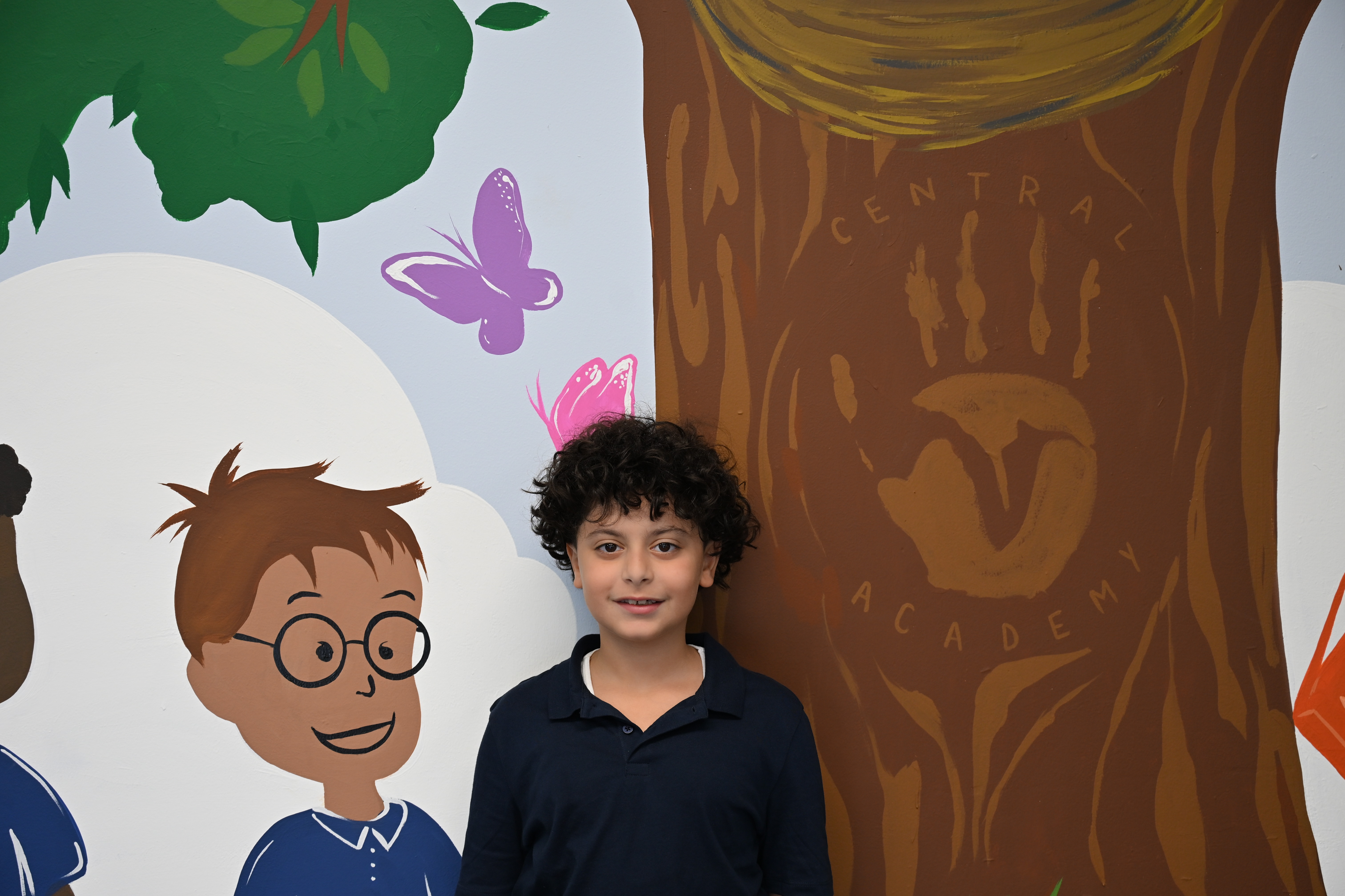 Central Academy student in front of school mural